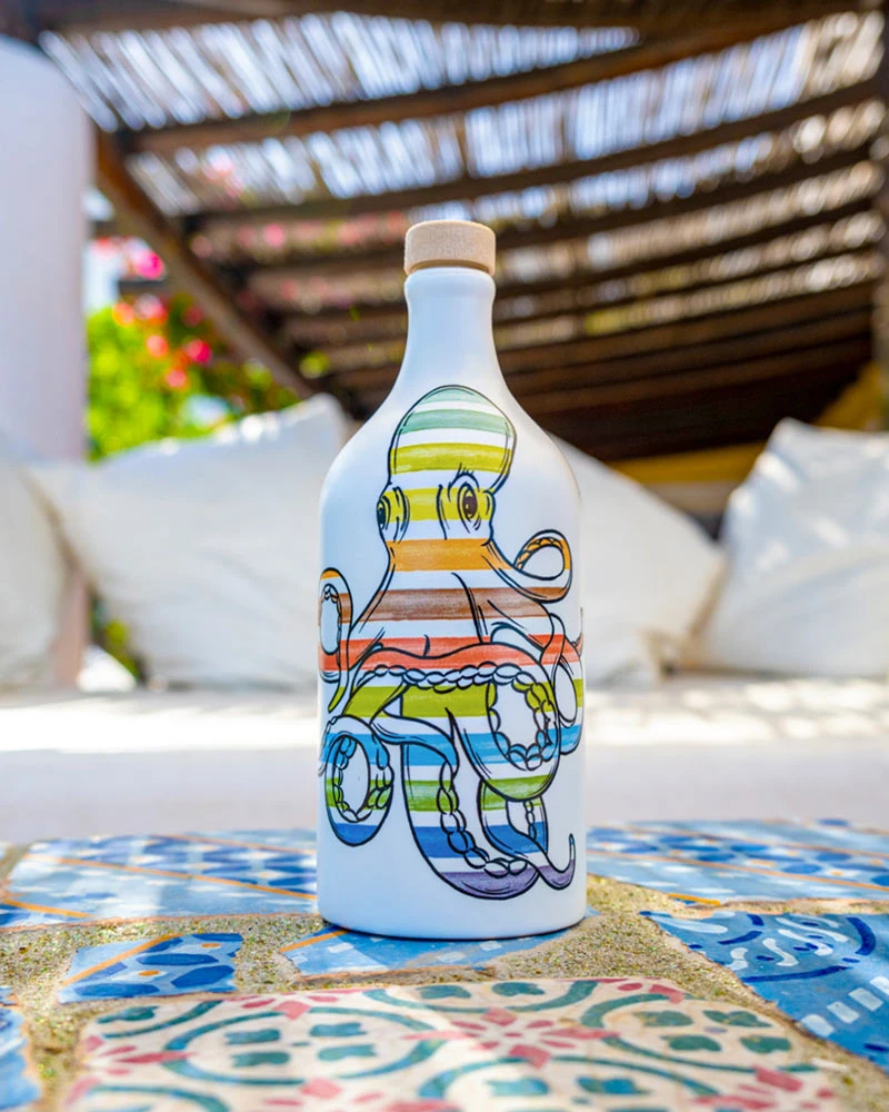 Muraglia Olivenöl - Tintenfisch Keramikflasche – Flasche im Hintergrund, in bunter Keramikflasche präsentiert