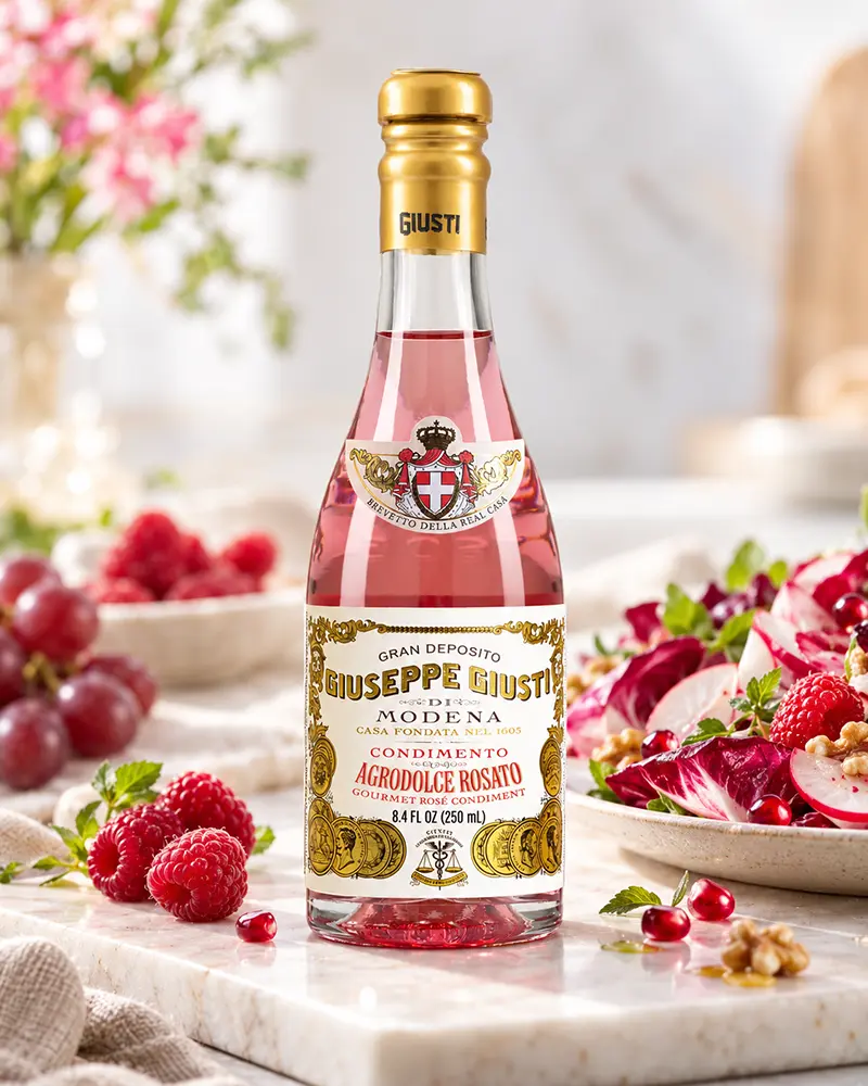 Giusti Agrodolce Rosato in der 250-ml-Flasche neben Himbeeren, Trauben und einem Radicchiosalat.