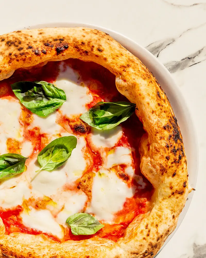 eine klassische Pizza Margherita liegt auf einem Teller