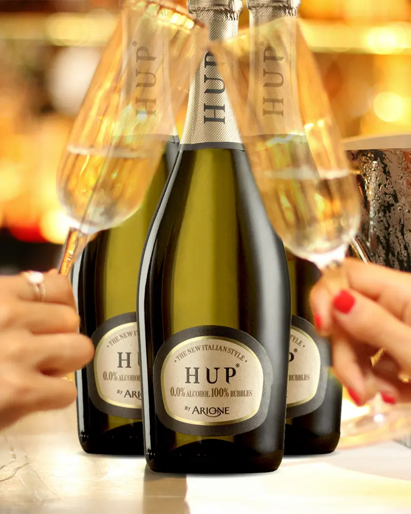 Drei Flaschen alkoholfreier HUP Sekt mit zwei gefüllten Sektgläsern im Vordergrund