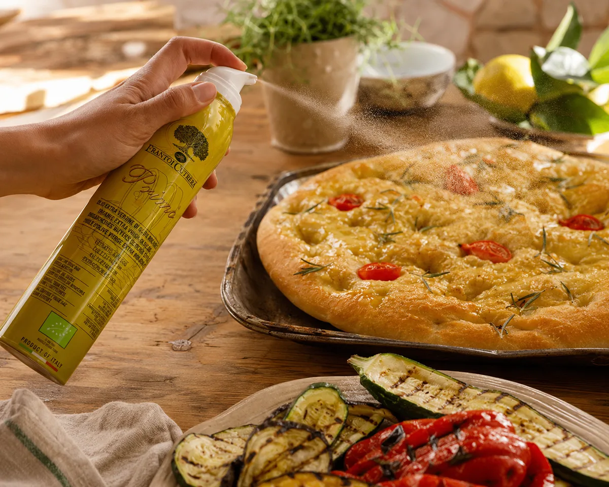 Bio-Olivenöl-Spray Primo von Frantoi Cutrera wird fein über Focaccia und gegrilltes Gemüse gesprüht.