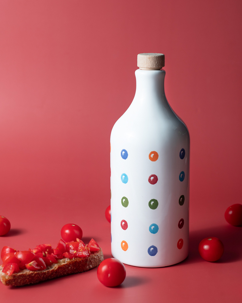Muraglia Olivenöl - Punkte Keramikflasche – Flasche im Hintergrund, in bunter Keramikflasche präsentiert
